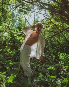 a man standing in the middle of a lush green forest