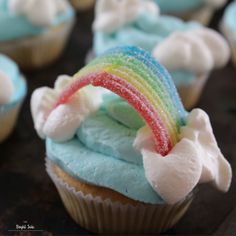 cupcakes with rainbow frosting and white icing on the top are sitting on a table