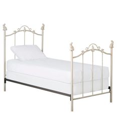 a metal bed frame with white sheets and pillows