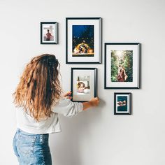 a woman is placing pictures on the wall