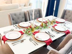 the table is set with plates and silverware, candlesticks and flowers on them