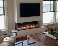 a living room with a fireplace and two chairs in front of the tv on the wall