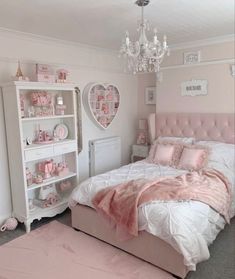 a bedroom decorated in pink and white with a chandelier