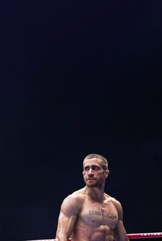 a shirtless man standing in the middle of a ring with his hands on his hips