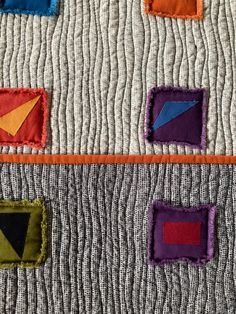 the quilt has different colored squares and shapes on it, along with an orange border