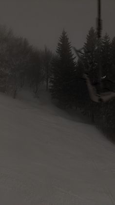 a person riding skis down a snow covered slope with trees in the back ground