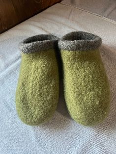 two pairs of green slippers sitting on top of a bed