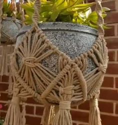 a potted plant with rope hanging from it's sides next to a brick wall