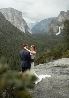 a bride and groom standing on top of a mountain