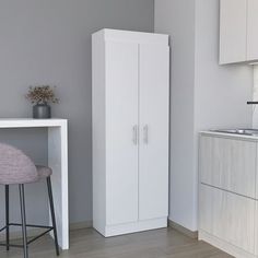 a kitchen with white cabinets and stools next to a counter top, in front of a gray wall