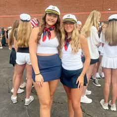 two young women in sailor outfits posing for a photo with other cheerleaders behind them