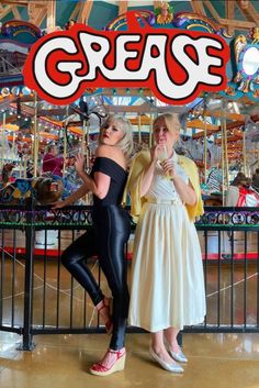 two women standing next to each other in front of a carousel