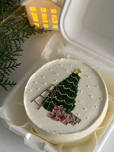 a decorated cake in a white box with a christmas tree on the front and side