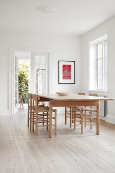 a table and chairs in a room with white walls, hardwood floors and doors leading to an outside patio