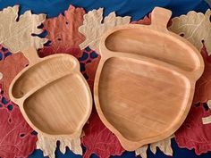 two wooden serving trays sitting on top of a red and blue tablecloth with leaves