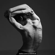 black and white photograph of a shirtless man with his hands on his head looking down