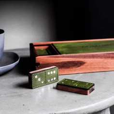 two wooden dominos sitting on top of a table next to a cup and saucer