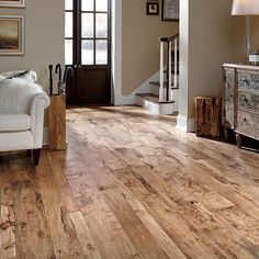 a living room with hardwood floors and white furniture in the corner, along with an entry way leading to another room