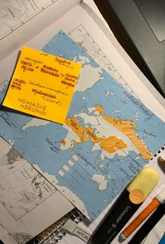 a yellow post - it note sitting on top of a map next to markers and pens