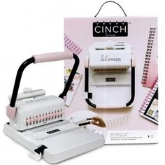 a white and black machine in front of a pink box with the instruction manual on it