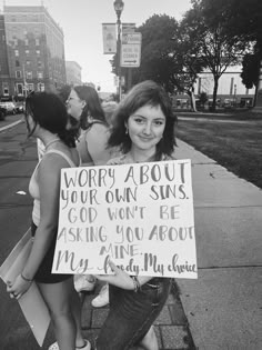 a woman holding a sign that says worry about your own suns god won't be asking you about my mine