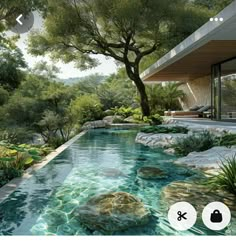 a pool surrounded by rocks and plants next to a house with trees in the background