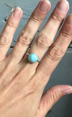 A stunning ethereal sky ocean blue round larimar has been set in sterling silver with a handmade ring band from sterling silver half dome wire. The stone is 11mm round and has interchanging hues of light and white running throughout. Choose your stone from the last photo in the listing. This will be the exact stone used in your ring!Larimar is the embodiment of the tranquil Sea and Sky energies. Its soft, soothing blues and calming turquoise is streaked with white patterns that resemble sunlight Adjustable Blue Larimar Ring, Turquoise Moonstone Ring In Sterling Silver, Adjustable Round Aquamarine Jewelry, Adjustable Aquamarine Round Jewelry, Adjustable Aquamarine Jewelry, Blue Larimar Round Rings, Adjustable Aquamarine Bracelet, Turquoise Larimar Cabochon Jewelry, Round Larimar Jewelry For Gifts