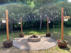 an outdoor fire pit surrounded by potted plants and hanging lights in the back yard