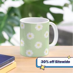 a green and white coffee mug with daisies on it