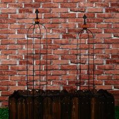 three metal birdcages sitting on top of a wooden box in front of a brick wall