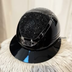 a black motorcycle helmet sitting on top of a white fur covered floor next to a window