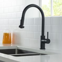 a black faucet over a kitchen sink next to a cup of orange juice