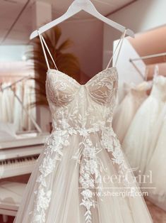 a dress hanging on a rack in front of a piano and other wedding gowns