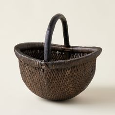 a brown basket sitting on top of a white table next to a black handlebar