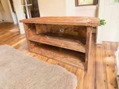 a wooden shelf sitting on top of a hard wood floor next to a rug and window