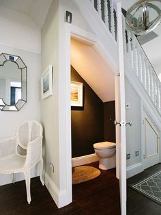 a white chair sitting under a stair case next to a toilet