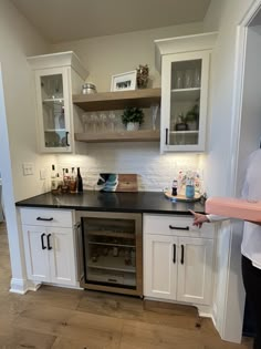 a kitchen with white cabinets, black counter tops and an oven in the center that has wine glasses on it