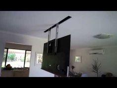 a television hanging from the ceiling in a living room