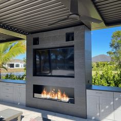 an outdoor fireplace with a television mounted on it's side and fire in the middle