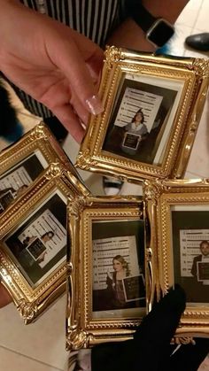 a person holding four framed pictures in their hands