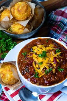 a bowl of chili with cheese and bread on the side