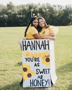 two girls in yellow shirts holding a sign that says hannah you're as sweet as honey