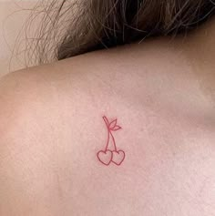 a small tattoo on the back of a woman's shoulder, with cherries