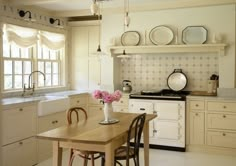 a kitchen filled with lots of white appliances and wooden table next to a stove top oven