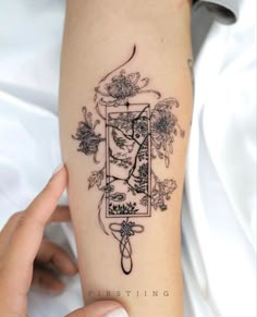 a woman's arm with a tattoo on it that has flowers and birds in the frame