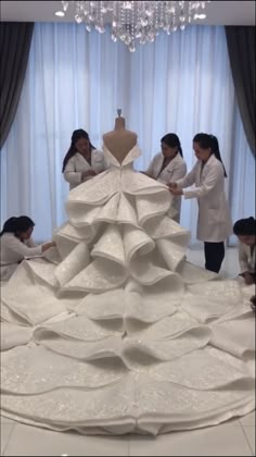 people standing around a dress made out of white fabric