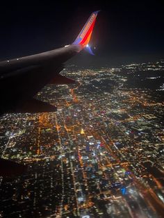 an airplane wing flying over a city at night