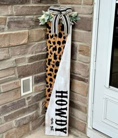 a cheetah print door hanger on the side of a brick building with a leopard print ribbon