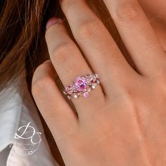 a woman's hand with a pink diamond ring on her left hand and the other hand holding an engagement ring