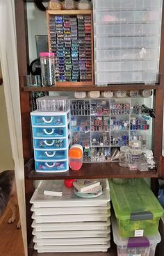 a shelf filled with lots of craft supplies on top of a hard wood floor next to a dog